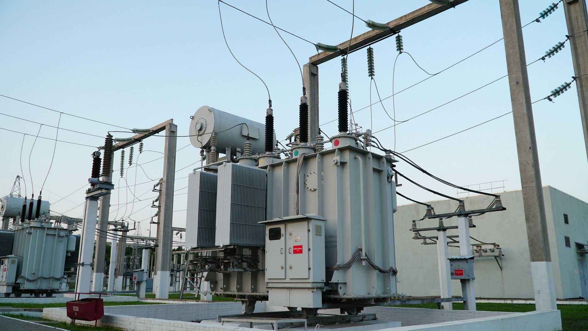 High voltage transformer against the blue sky. Electric current redistribution substation